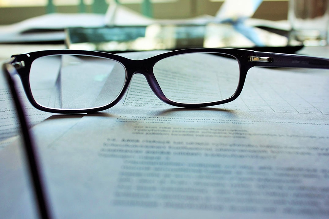 Photo of a pair of reading glasses on top of a printed contract